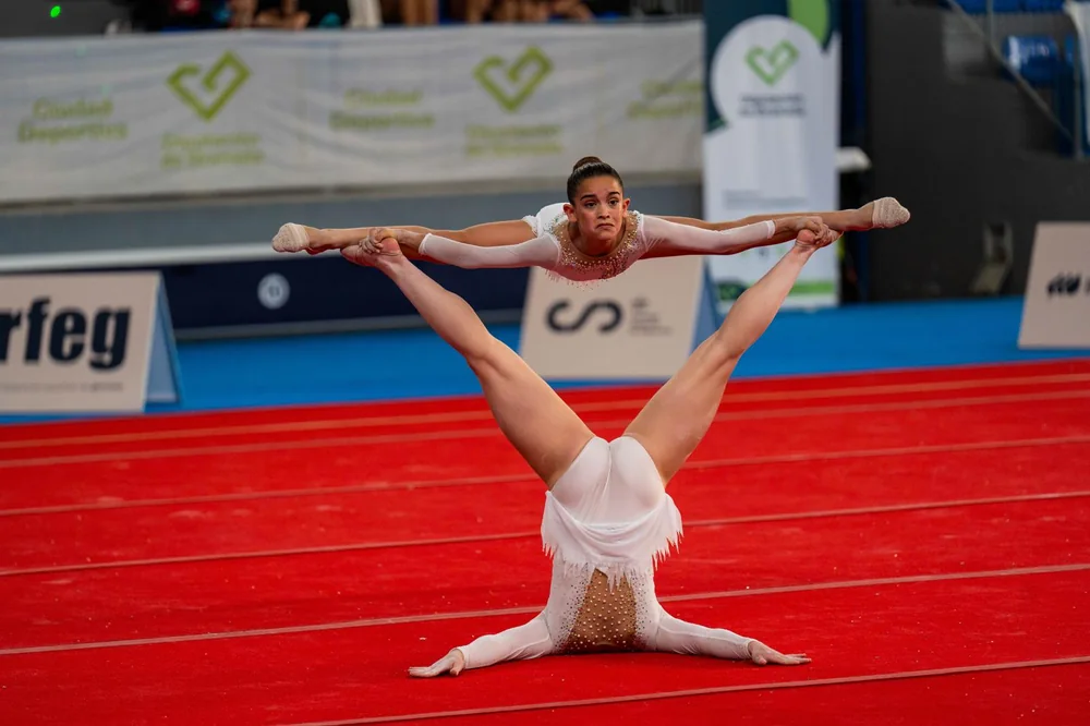 Two gymnasts performing a partner balance during a competition