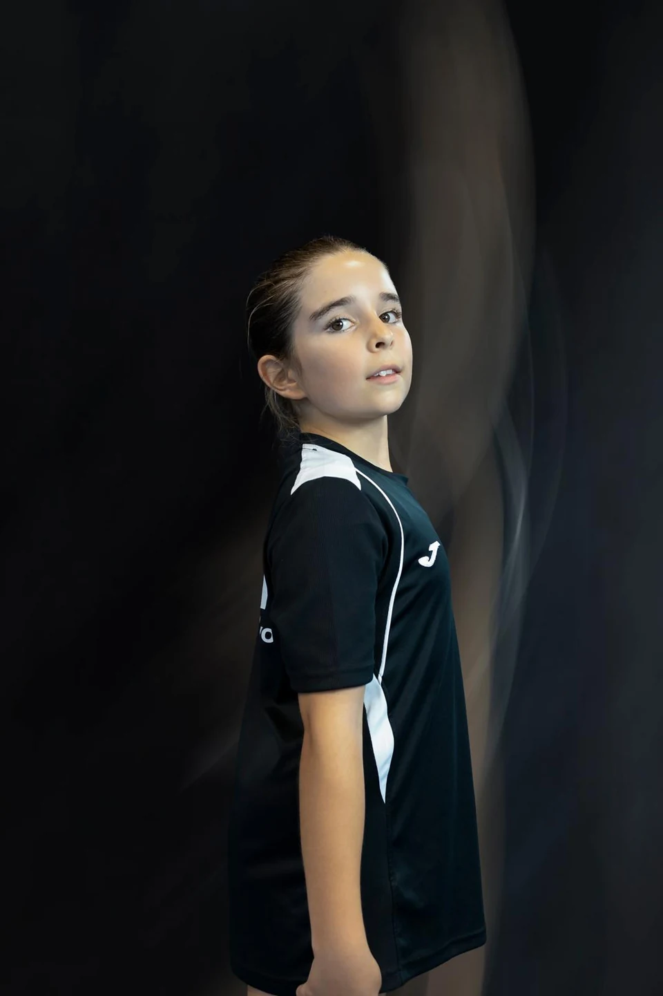 Retrato de una gimnasta con la camiseta del club sobre fondo oscuro