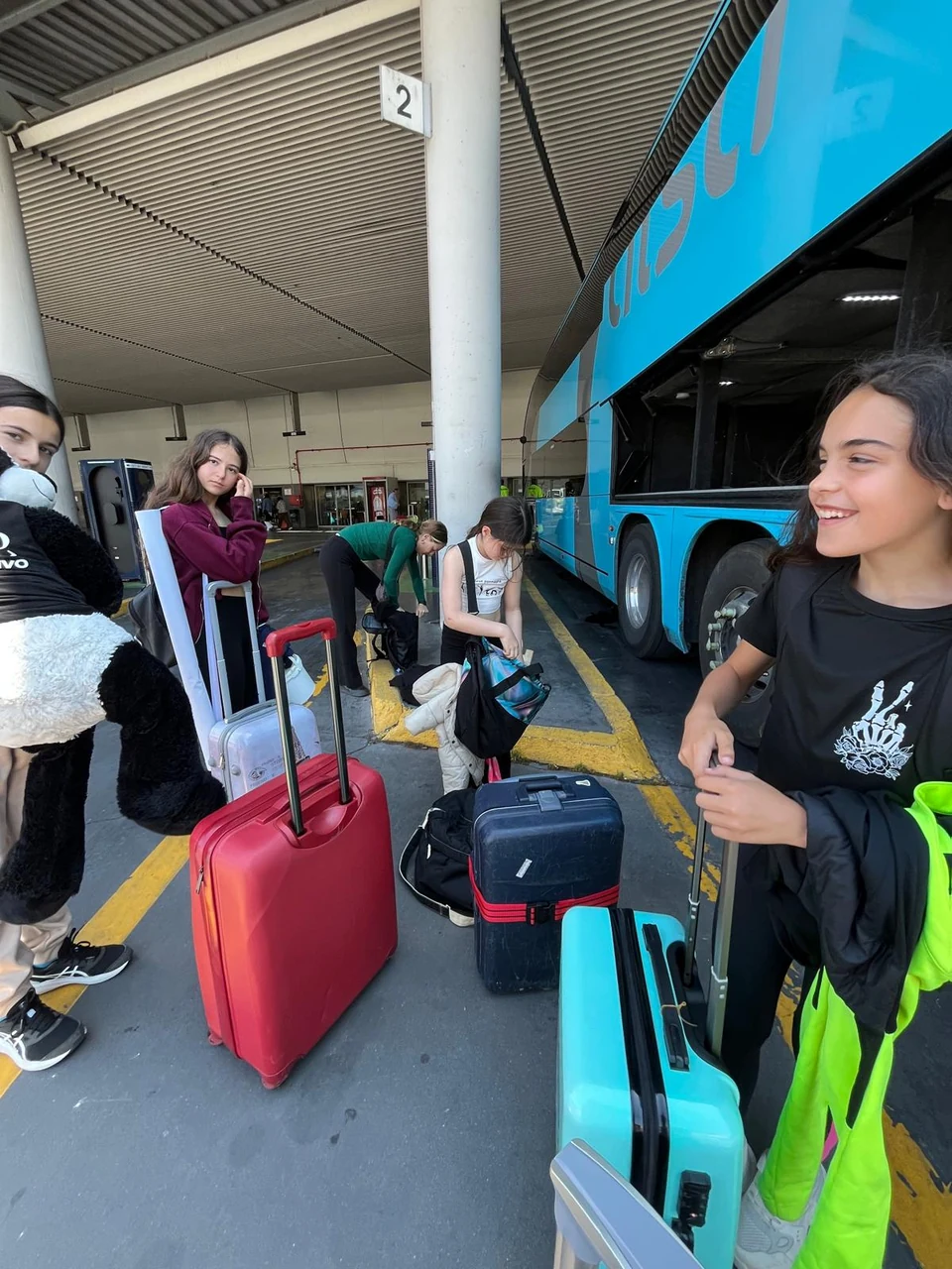 Gimnastas del club con sus maletas junto al autobús en la estación